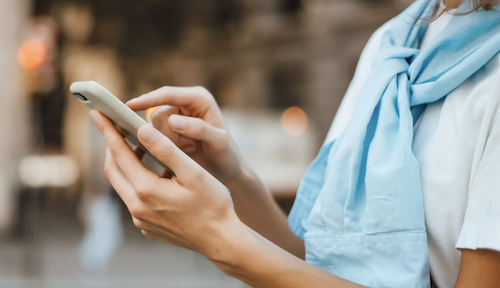 femme téléphone à la main sans voir le visage Comment téléphoner aux USA ? Odyssée Américaine