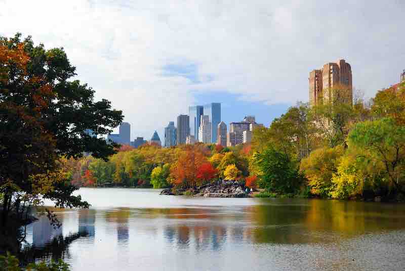New York City Manhattan Central Park panorama in Autumn lake with skyscrapers and colorful trees with reflection.